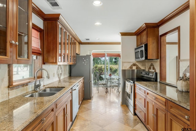 kitchen featuring ornamental molding, appliances with stainless steel finishes, sink, and light stone counters