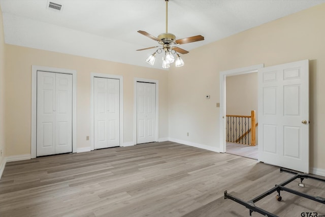 unfurnished bedroom featuring light hardwood / wood-style floors, ceiling fan, and two closets