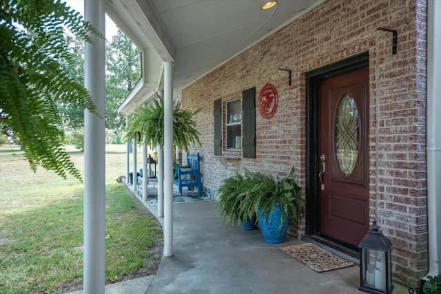 doorway to property featuring a lawn and covered porch