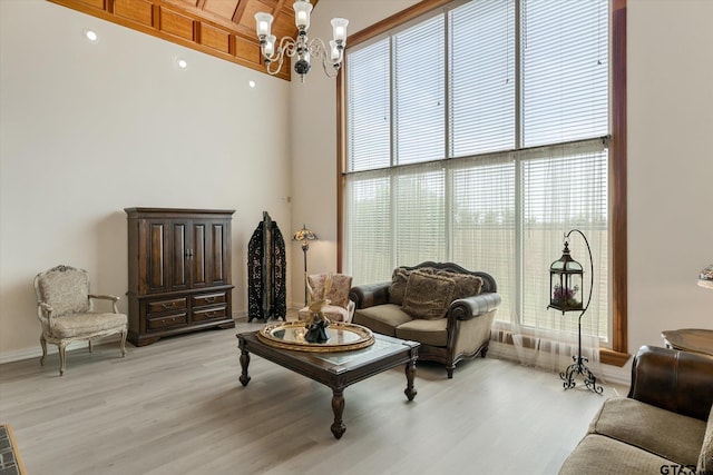 living room with a towering ceiling, a chandelier, and light hardwood / wood-style floors