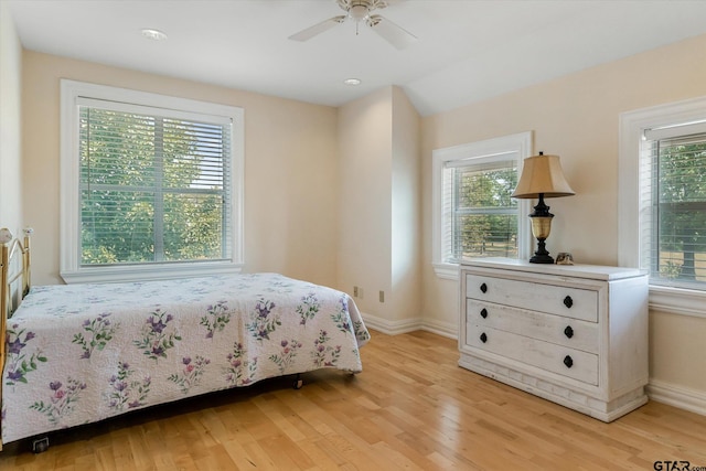 bedroom with ceiling fan, multiple windows, and light hardwood / wood-style flooring