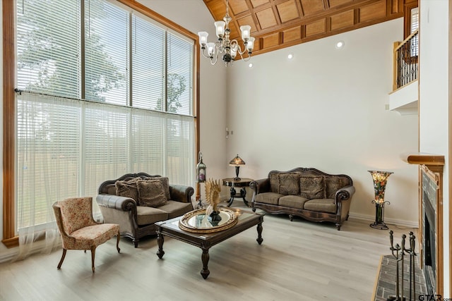 living room with an inviting chandelier, a towering ceiling, and light wood-type flooring