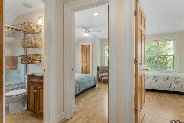 bedroom with ensuite bathroom, light hardwood / wood-style floors, and ceiling fan