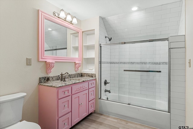 full bathroom featuring hardwood / wood-style flooring, enclosed tub / shower combo, vanity, and toilet