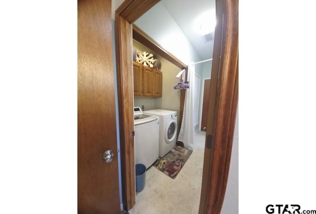 clothes washing area featuring light colored carpet, cabinet space, and washer and dryer