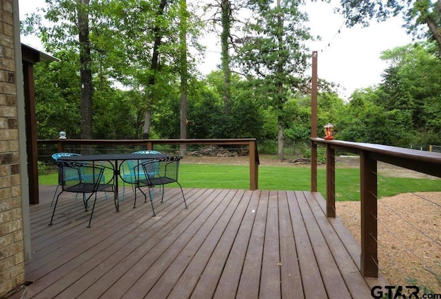 wooden terrace with outdoor dining area and a lawn