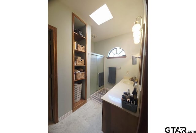 bathroom with a shower stall, a sink, and a skylight