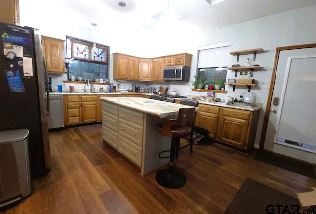 kitchen featuring a kitchen breakfast bar, dark wood finished floors, light countertops, a kitchen island, and appliances with stainless steel finishes