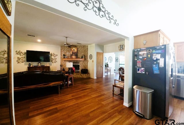 living room featuring visible vents, dark wood-style flooring, a ceiling fan, and a fireplace