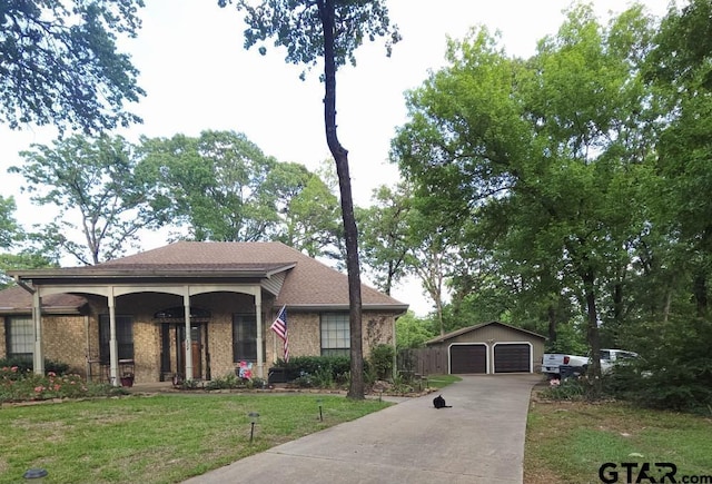 view of front of house with an outbuilding, brick siding, a garage, roof with shingles, and a front lawn