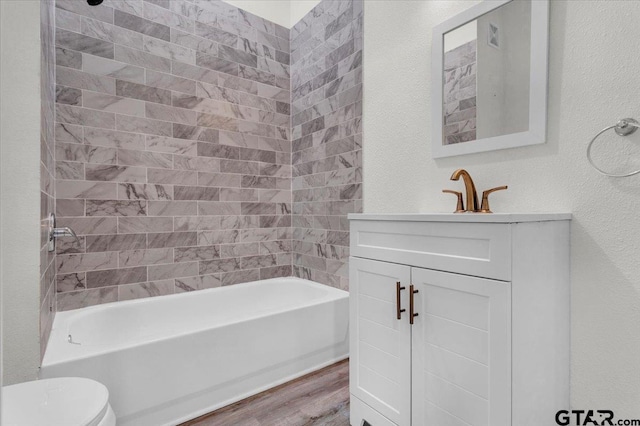 full bathroom with wood-type flooring, tiled shower / bath combo, toilet, and vanity