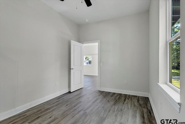 empty room with ceiling fan, wood-type flooring, and a healthy amount of sunlight