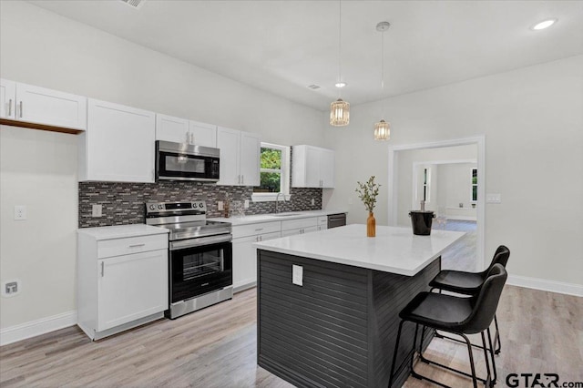 kitchen with pendant lighting, white cabinetry, and appliances with stainless steel finishes