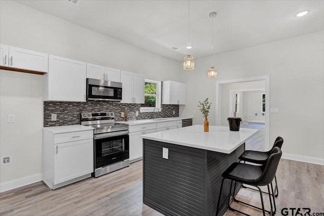 254 SE 19th St, Paris, TX 75460 - kitchen with stainless steel appliances, white cabinets, a kitchen breakfast bar, a kitchen island, and decorative backsplash