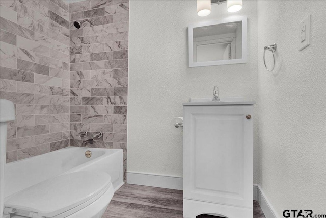 full bathroom with toilet, tiled shower / bath combo, vanity, and hardwood / wood-style floors