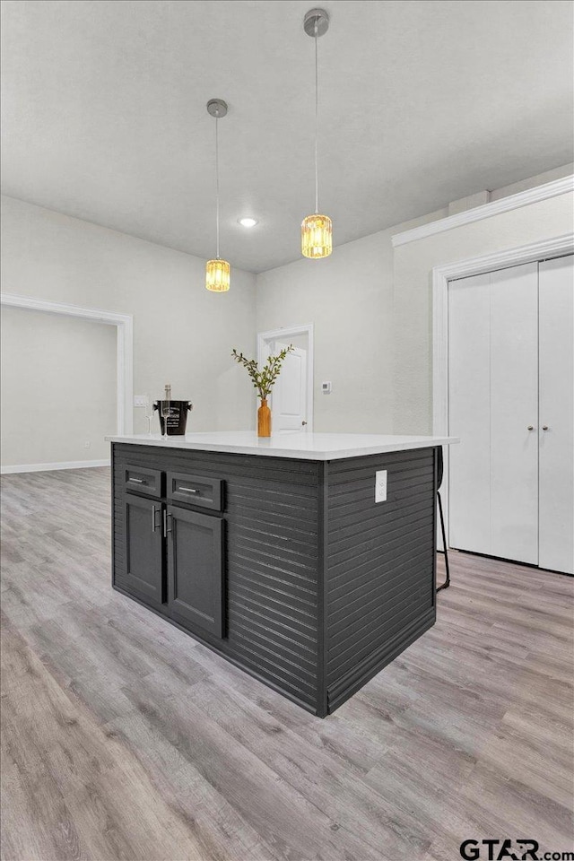 kitchen featuring light wood-type flooring, a kitchen breakfast bar, pendant lighting, and a center island