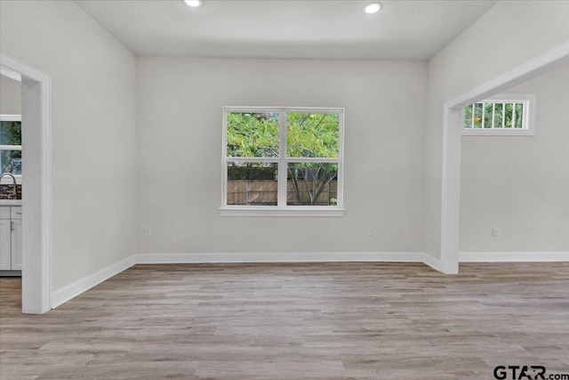 spare room with plenty of natural light, sink, and light wood-type flooring