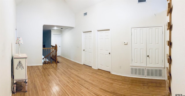 corridor featuring light hardwood / wood-style flooring and high vaulted ceiling