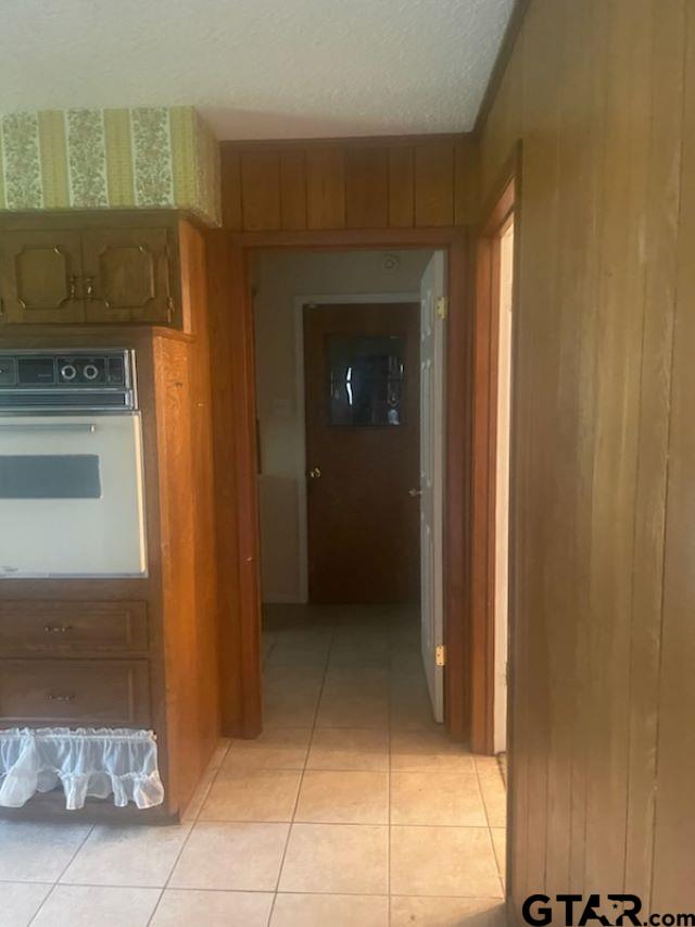 779 E Texas St, Van, TX 75790 - corridor featuring light tile patterned floors, a textured ceiling, and wood walls