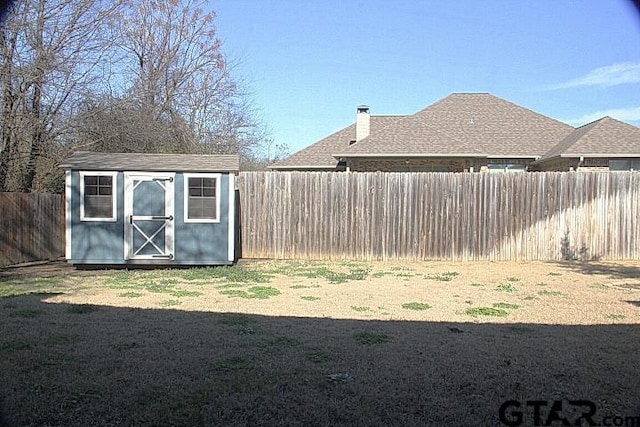 view of yard featuring an outbuilding, a fenced backyard, and a storage unit