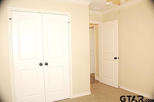 unfurnished bedroom featuring crown molding, baseboards, a closet, and light colored carpet