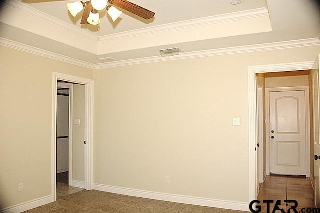 carpeted empty room with baseboards, a tray ceiling, a ceiling fan, and crown molding