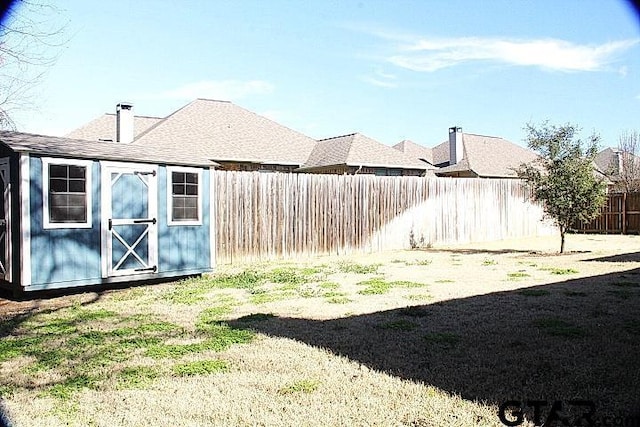 view of yard with a storage shed, a fenced backyard, and an outdoor structure