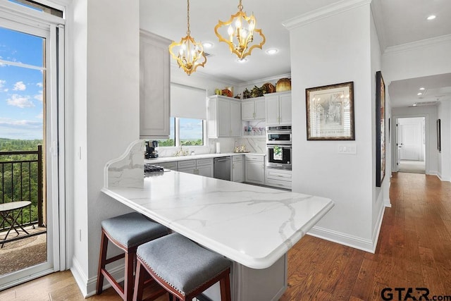 2801 Wexford Dr, Tyler, TX 75709 - kitchen with appliances with stainless steel finishes, a chandelier, a peninsula, dark wood-style flooring, and ornamental molding