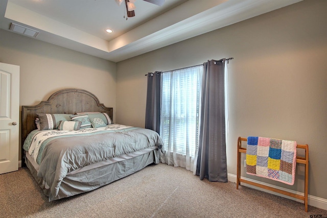 bedroom featuring ceiling fan, carpet floors, and a tray ceiling