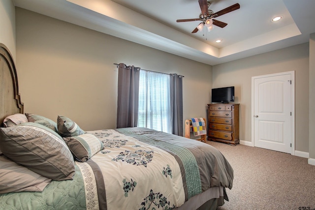 carpeted bedroom with ceiling fan and a raised ceiling