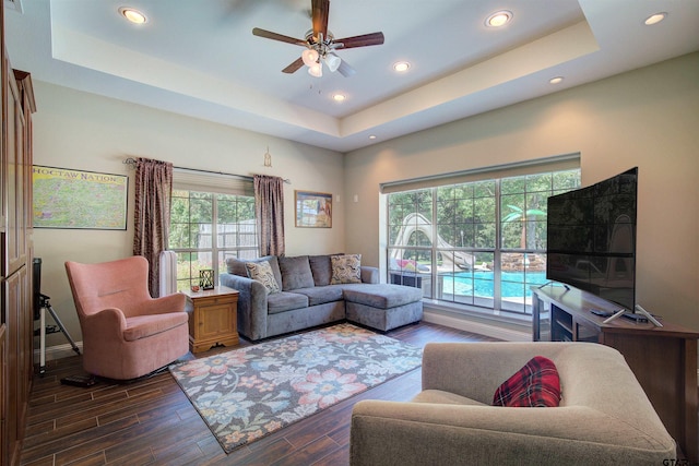 living room with ceiling fan and a raised ceiling