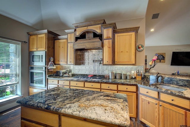 kitchen with sink, backsplash, dark stone countertops, and appliances with stainless steel finishes