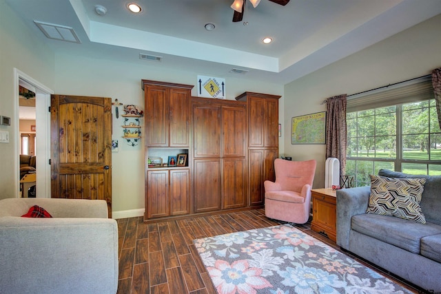 living room featuring ceiling fan and a raised ceiling