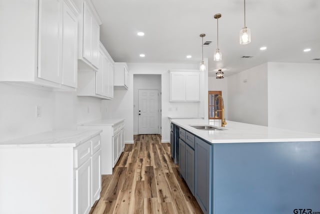 kitchen featuring pendant lighting, white cabinets, blue cabinets, sink, and light hardwood / wood-style flooring