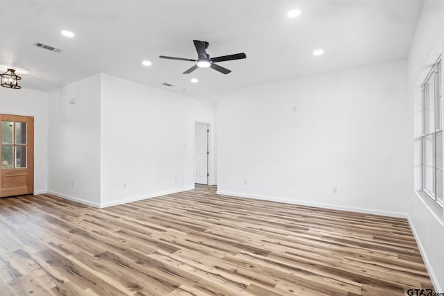 spare room with ceiling fan with notable chandelier and light hardwood / wood-style flooring