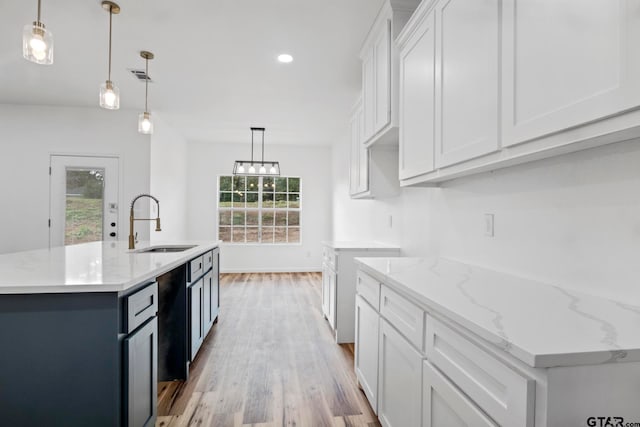 kitchen featuring a kitchen island with sink, sink, hanging light fixtures, light hardwood / wood-style flooring, and white cabinetry