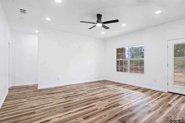 empty room with ceiling fan, plenty of natural light, and light wood-type flooring