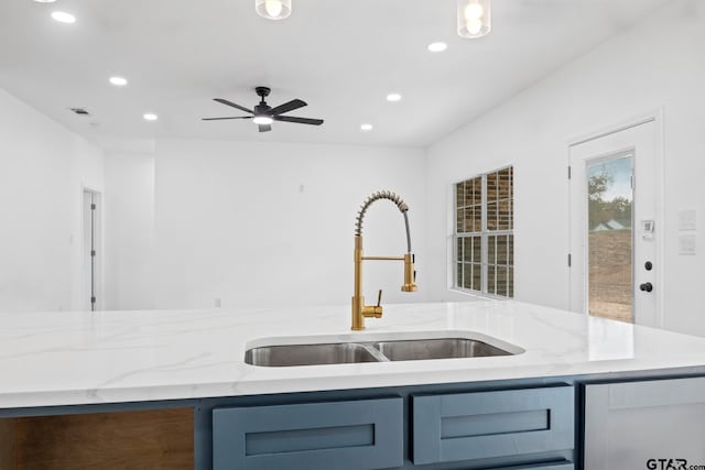 kitchen featuring light stone countertops, ceiling fan, and sink