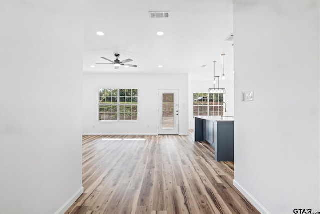 unfurnished living room with ceiling fan, light hardwood / wood-style floors, and sink