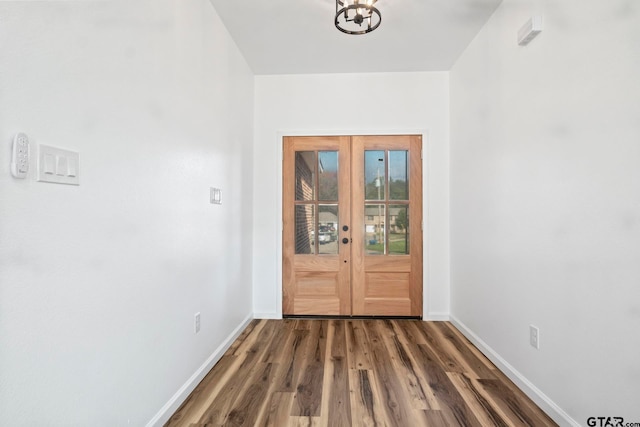 doorway with french doors, an inviting chandelier, and dark wood-type flooring