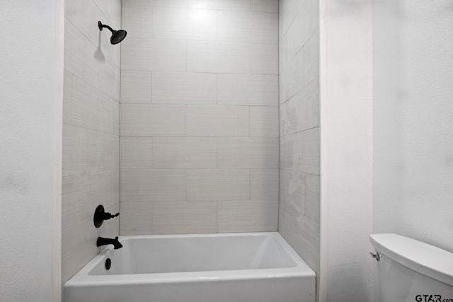 bathroom featuring tiled shower / bath combo and toilet