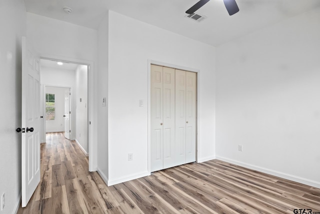 unfurnished bedroom with a closet, light hardwood / wood-style flooring, and ceiling fan