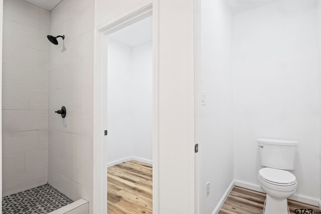 bathroom featuring tiled shower, hardwood / wood-style floors, and toilet