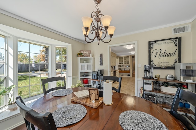 tiled dining room featuring a notable chandelier and ornamental molding