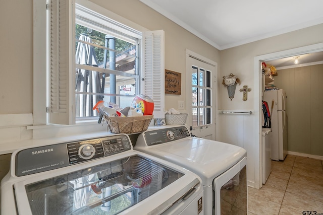 laundry area with washing machine and clothes dryer, light tile patterned floors, and crown molding