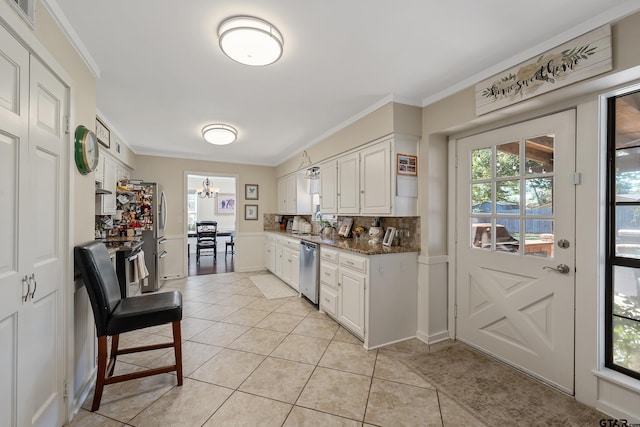 kitchen featuring dark stone counters, white cabinetry, appliances with stainless steel finishes, light tile patterned floors, and decorative backsplash