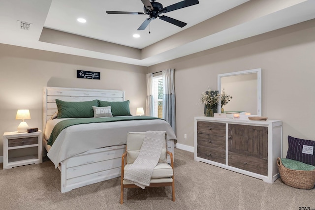 carpeted bedroom featuring a tray ceiling and ceiling fan