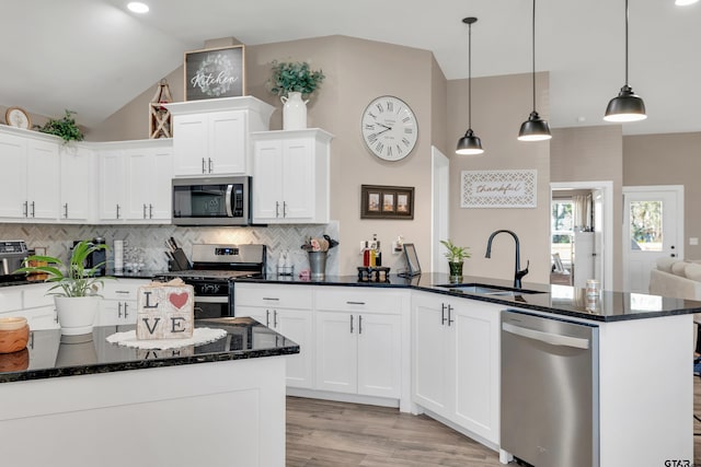 kitchen with sink, decorative light fixtures, vaulted ceiling, and stainless steel appliances