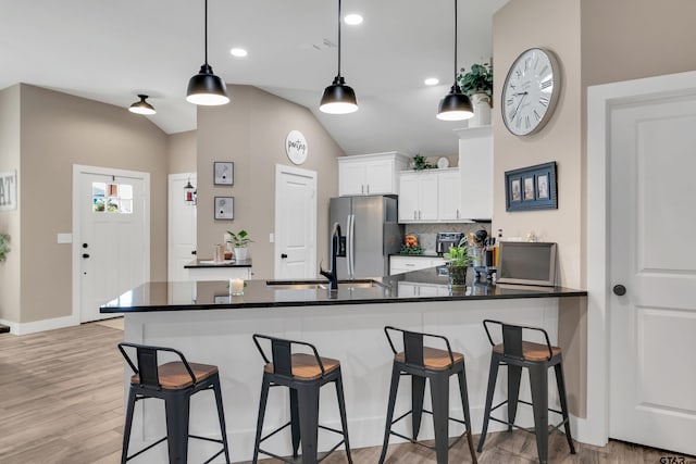 kitchen featuring pendant lighting, white cabinets, lofted ceiling, backsplash, and stainless steel fridge with ice dispenser