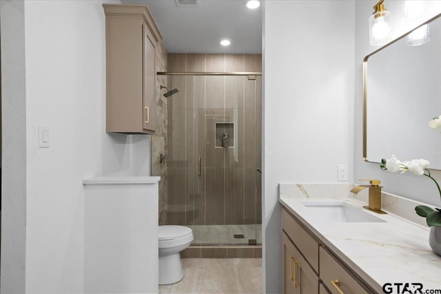 bathroom featuring tile patterned floors, a shower with door, vanity, and toilet